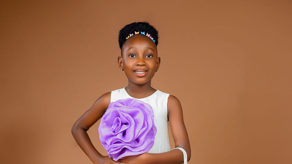 Young girl in a white dress with purple floral decorations against a brown background